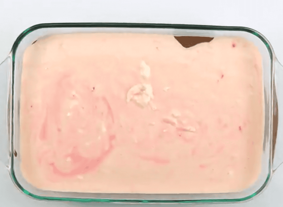 Cheesecake mixture over the brownie mixture in a glass baking dish. 