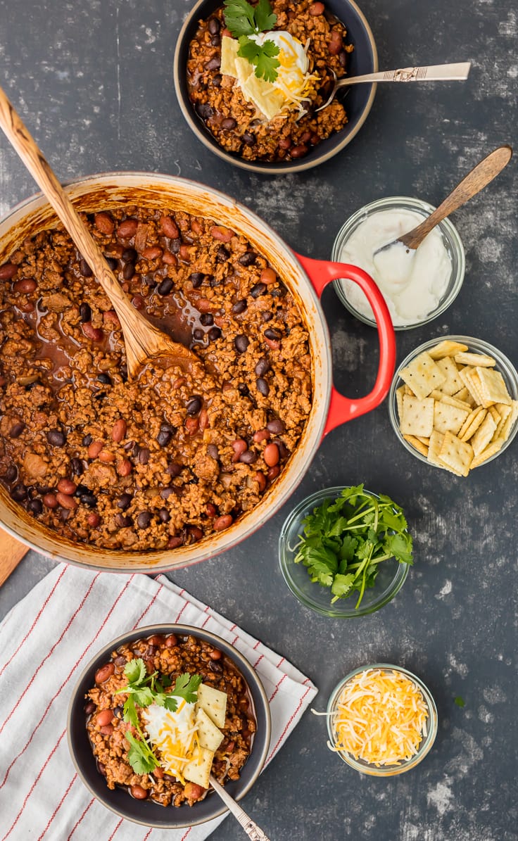 large pot of chili surrounded by bowls of ingredients
