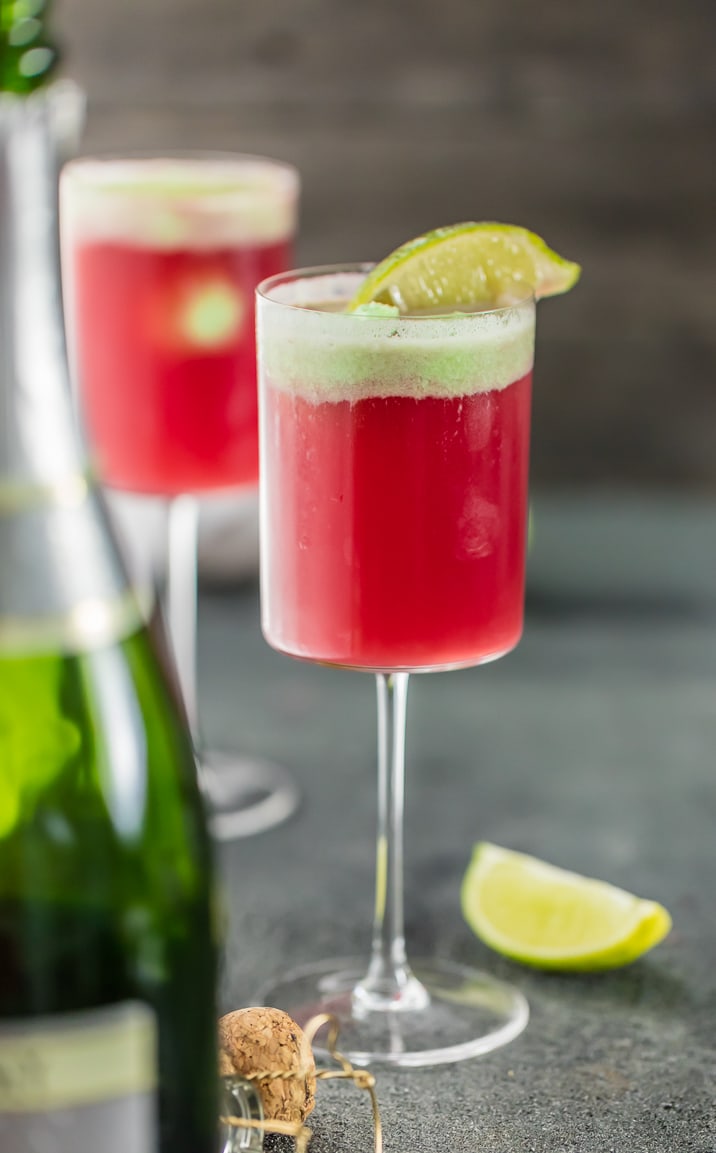 glass of cranberry limeade holiday champagne punch with lime wedge