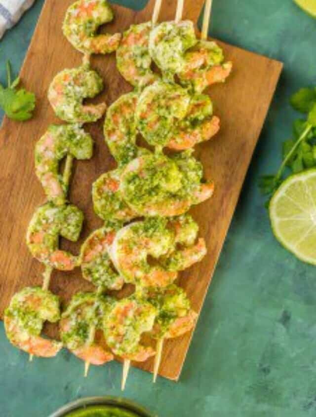 pesto shrimp skewers on a wooden cutting board