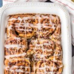 cinnamon roll french toast bake in a white baking dish drizzled with frosting