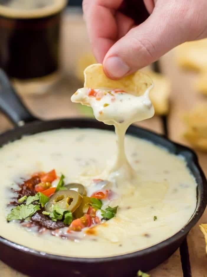 up close shot of dipping chip into melted cheese dip
