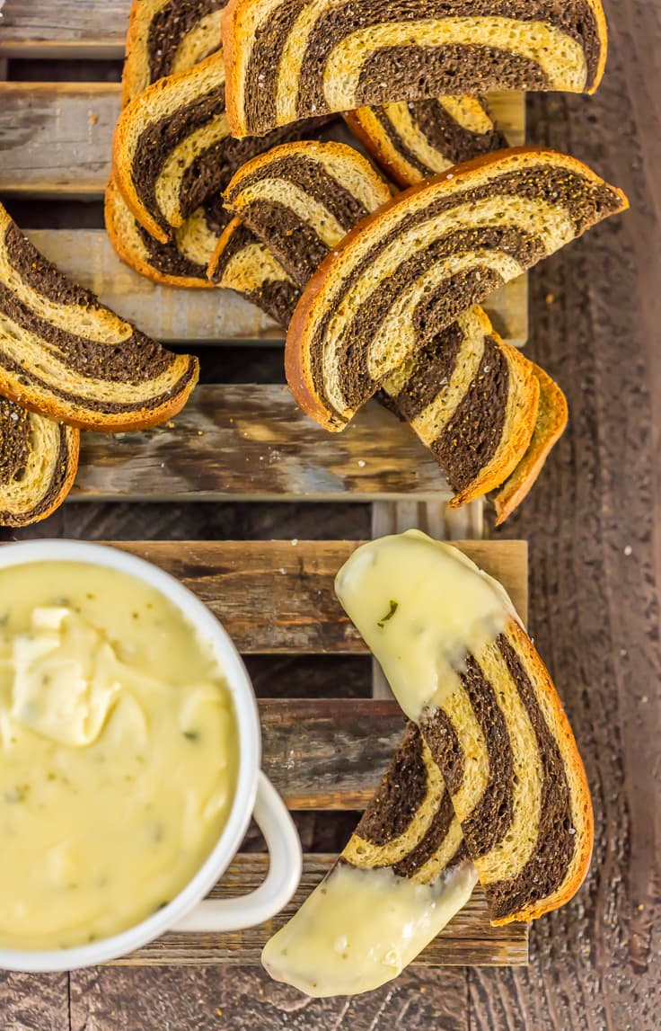 top view of marbled rye crostini slices and a bowl of fondue on wooden palate