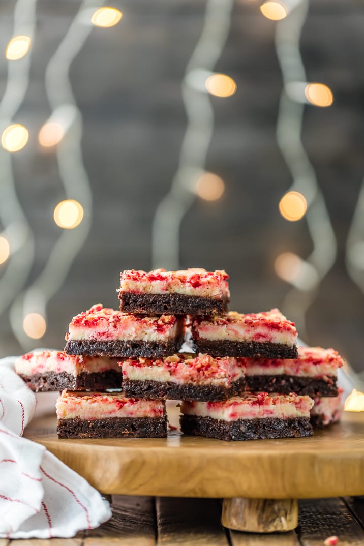 A stack of peppermint cheesecake brownies with string lights blurred in the background