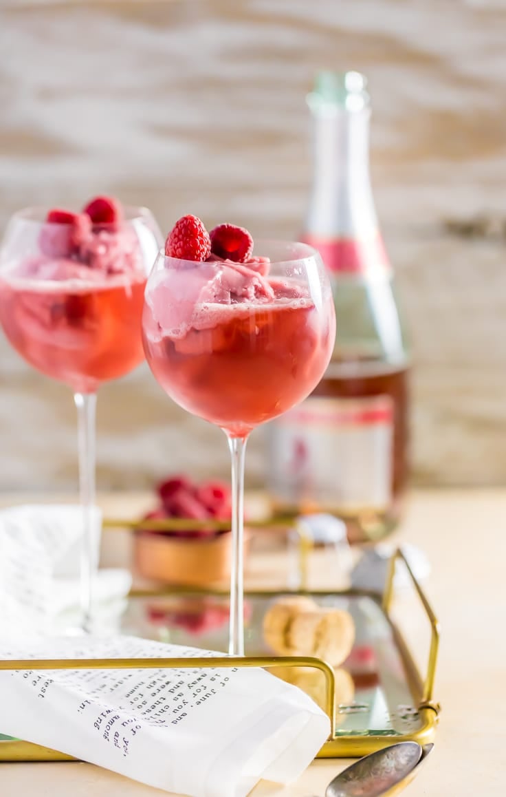 two wine glasses filled with raspberry champagne floats