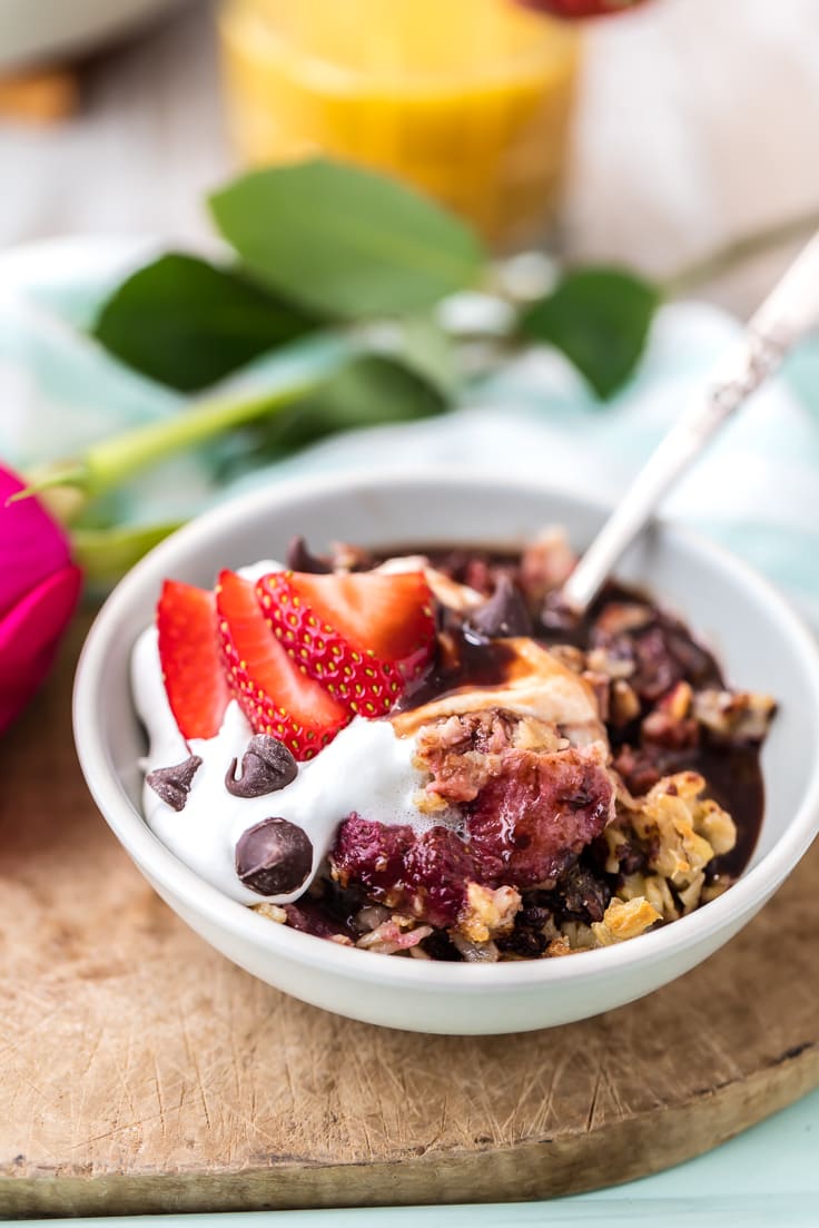 strawberry chocolate oatmeal in a white bowl, topped with whipped cream and strawberries