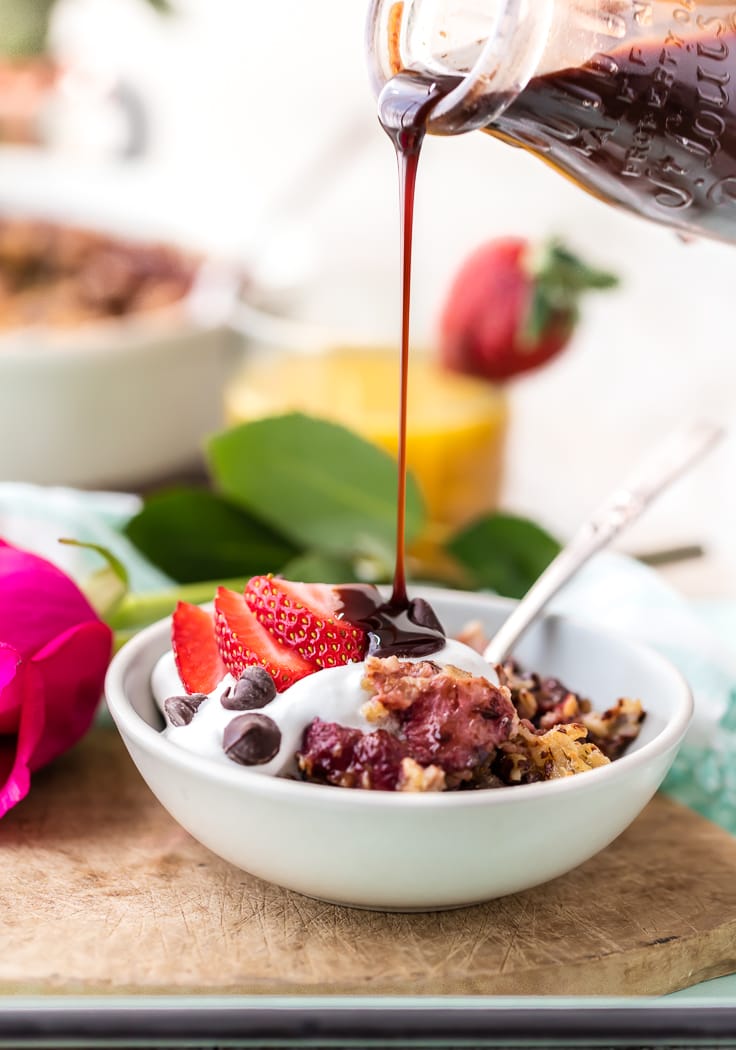 pouring chocolate sauce over a bowl of baked oatmeal