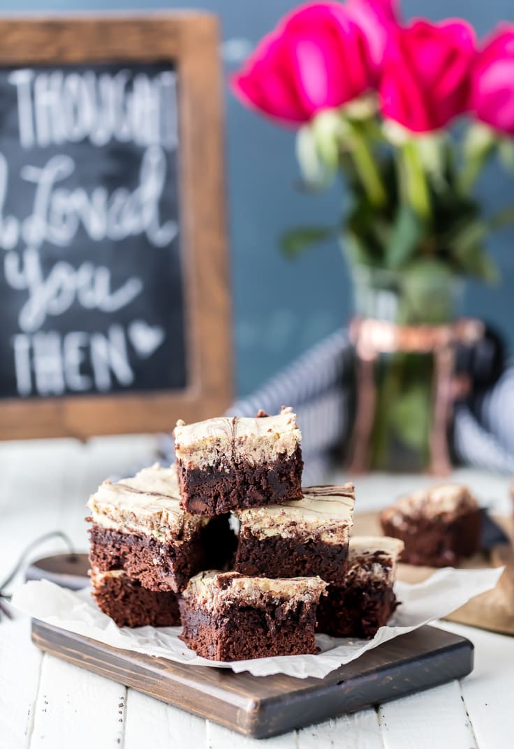 cream cheese brownies stacked up on a cutting board