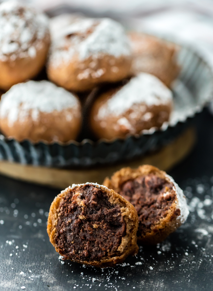 fried brownie bites broken in half, in front of a plate of brownie bites