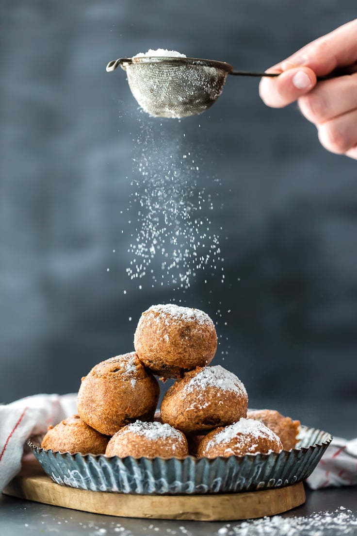 sprinkling powdered sugar over a plate of fried brownie bites