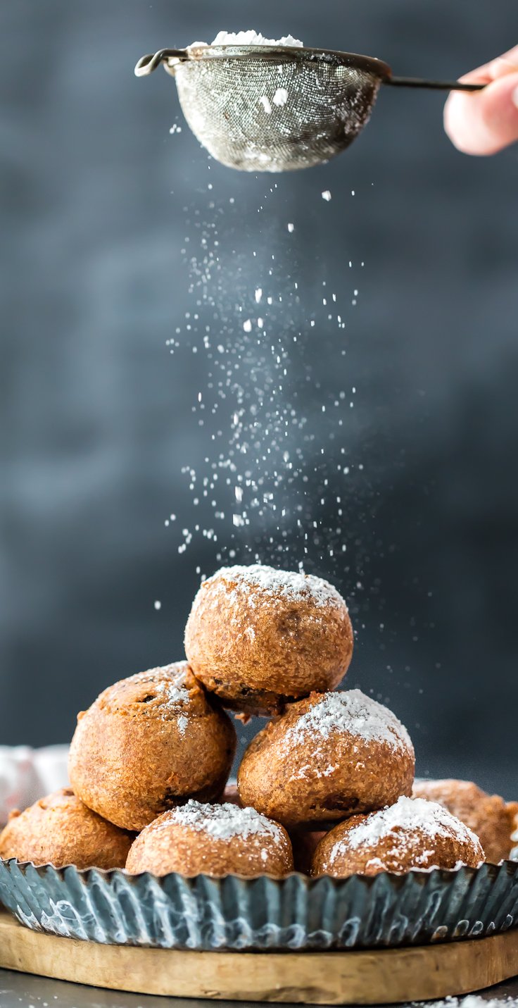 sprinkling powdered sugar over a plate of fried brownie truffles