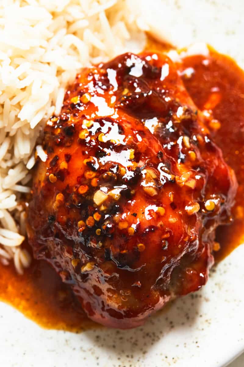 up close honey garlic chicken thigh with rice on plate