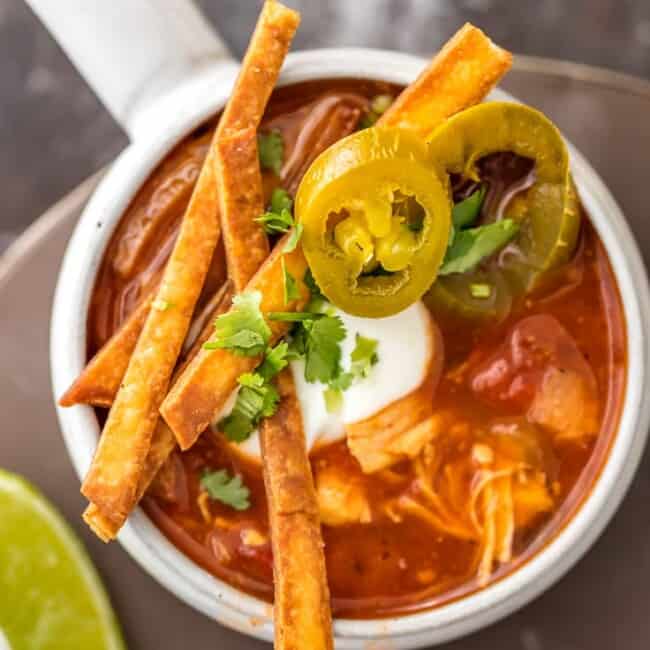 Skinny Slow Cooker Chicken Tortilla Soup is my absolute FAVORITE SOUP recipe for Winter! Spicy, easy, and delicious. Throw all the ingredients in a crockpot and you're done! Easy fried tortillas make the perfect topper!