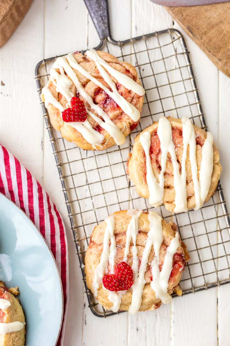 three strawberry cinnamon roll cookies arranged on a cooling rack