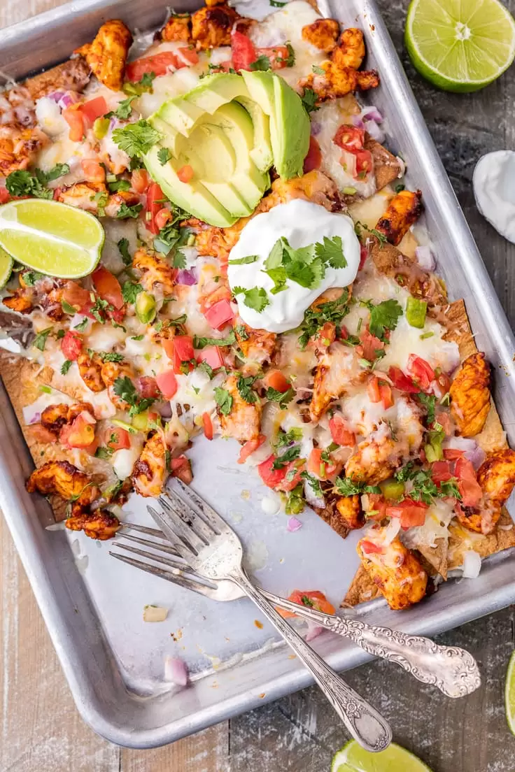 Chicken Nachos are great for feeding a crowd! This Tequila Lime Baked Chicken Nachos recipe is just AMAZING! These easy sheet pan nachos are so delicious, and perfect for any occasion. chicken nachos in a sheet pan