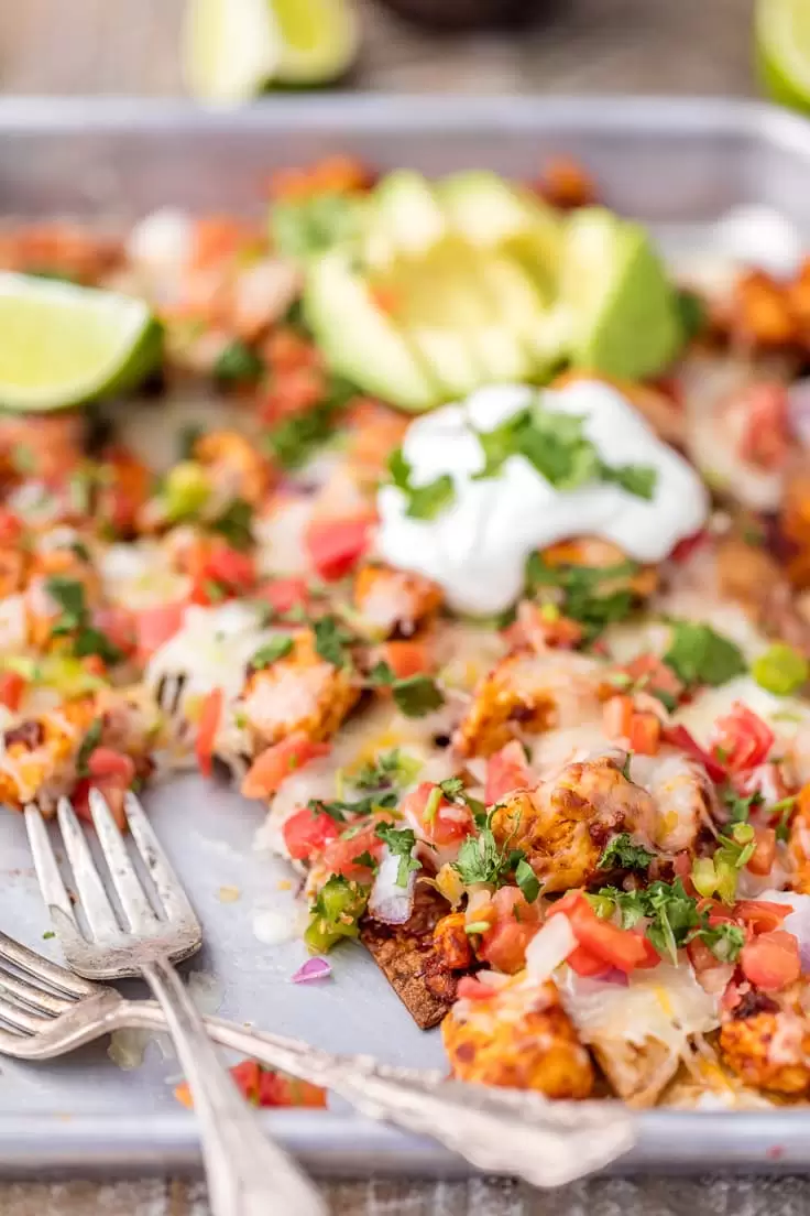 Chicken Nachos are great for feeding a crowd! This Tequila Lime Baked Chicken Nachos recipe is just AMAZING! These easy sheet pan nachos are so delicious, and perfect for any occasion. sheet pan chicken nachos
