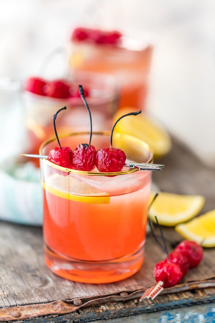 whiskey sours garnished with cherries and sliced lemons