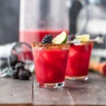 two spicy blackberry margaritas garnished with fruit