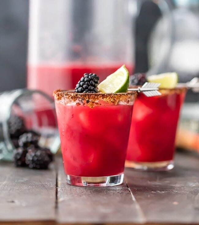 Blackberry Margaritas for a crowd are THE BEST margaritas ever! Even better, this is a fun and SPICY margarita recipe. This easy cocktail recipe uses tequila, blackberry brandy, green chiles, fresh fruit, agave, orange juice, and lime. Rimmed with chili salt. Cheers!