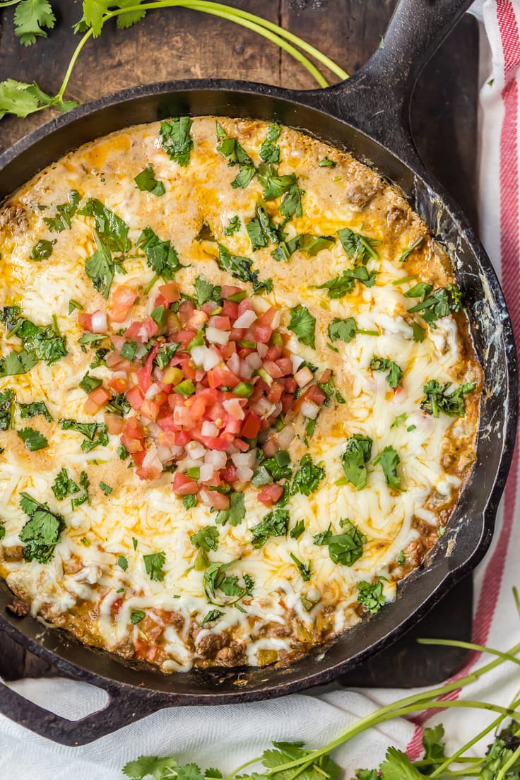 cheesy dip in skillet topped with pico de gallo and cilantro