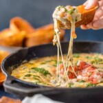 close up view of a chip scooping out dip in a skillet