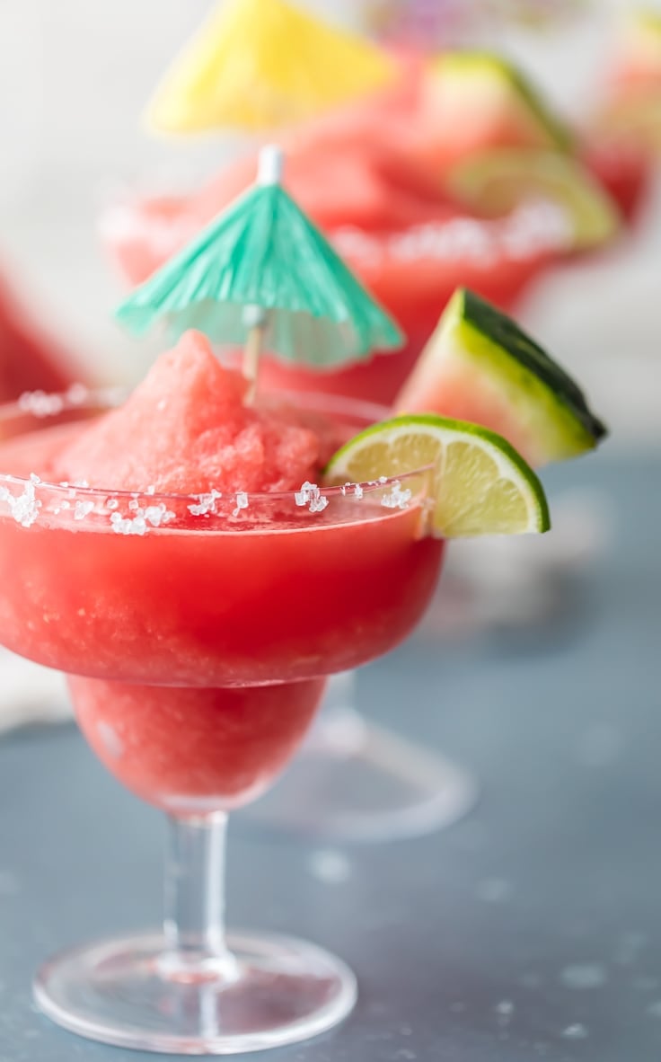 a frozen watermelon margarita garnished with fresh watermelon and a paper cocktail umbrella