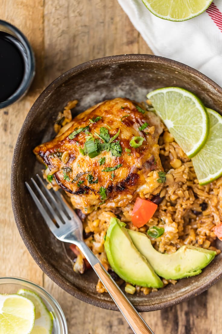 close up of plate of chicken, rice, avocados, and lime