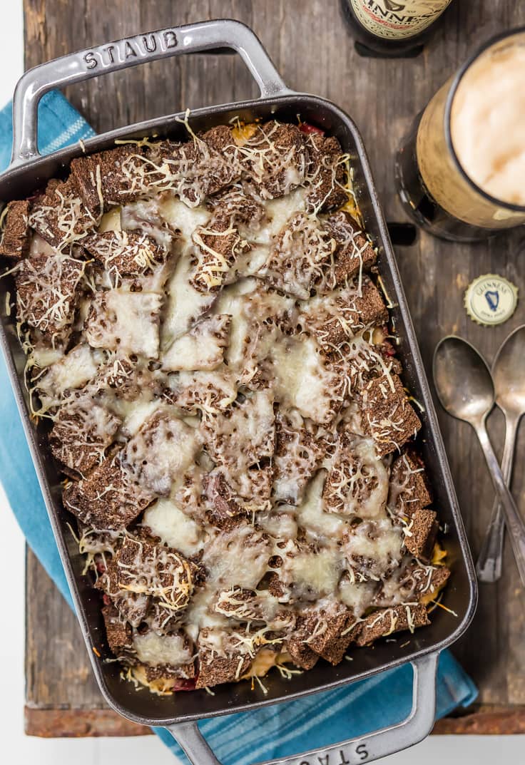 overhead view of corned beef casserole topped with rye bread and Swiss cheese, on a rustic table top background