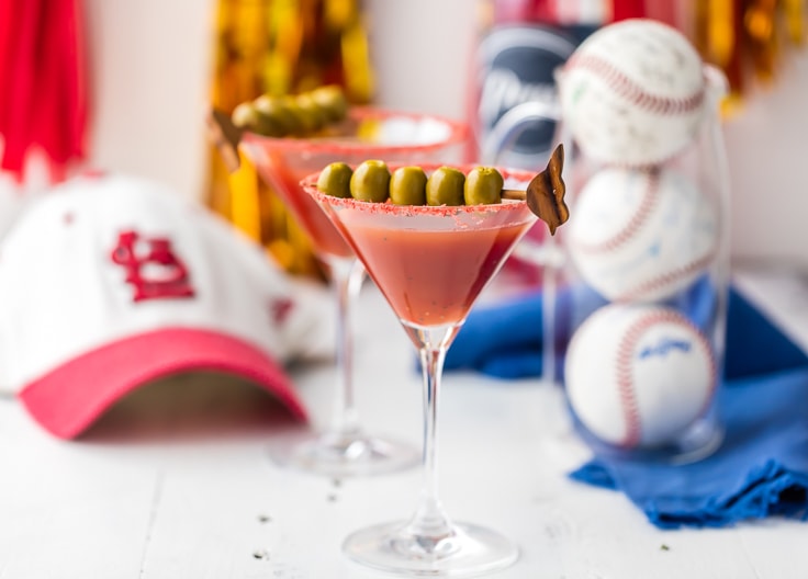 red martini next to baseball hat and baseballs