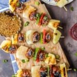 grilled meat skewers on a wooden cutting board.