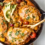 a top view of enchilada stuffed chicken in a skillet with wooden spoon