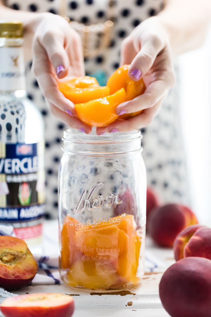 placing peach slices into a mason jar