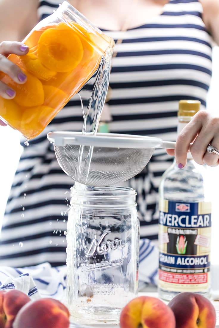 pouring peach infused vodka through a strainer