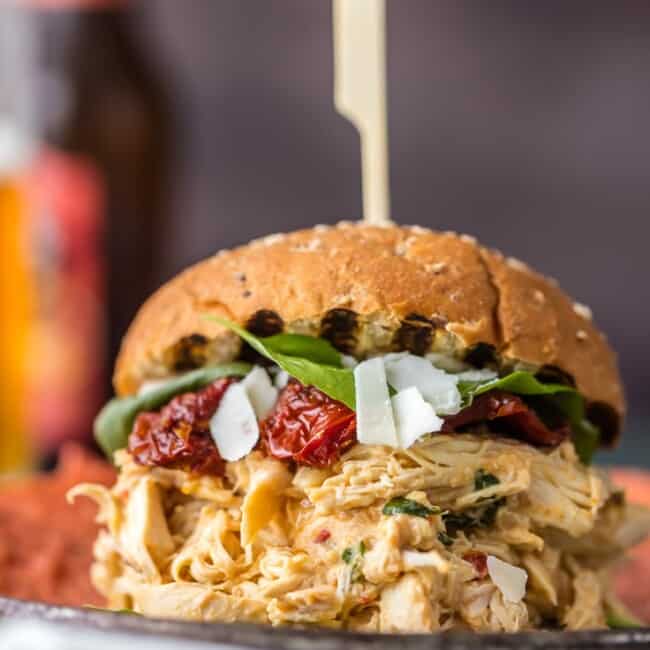 These SLOW COOKER CHICKEN ALFREDO SANDWICHES are simple, easy, and delicious. A quick and easy crockpot meal the entire family will love. Topped with sun dried tomatoes, basil, and parmesan. PERFECTION!