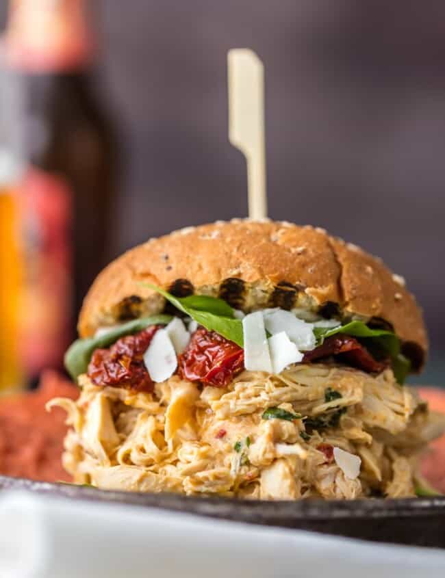 These SLOW COOKER CHICKEN ALFREDO SANDWICHES are simple, easy, and delicious. A quick and easy crockpot meal the entire family will love. Topped with sun dried tomatoes, basil, and parmesan. PERFECTION!