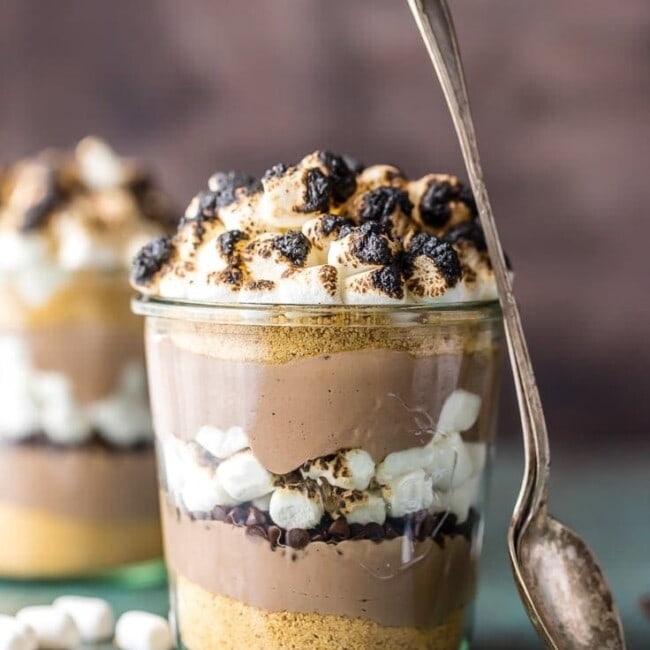 This S'mores Breakfast Parfait recipe is sure to make your mornings great! This delicious s'mores inspired recipe is loaded with Greek yogurt, protein powder, graham cracker crumbs, chocolate chips, and toasted marshmallows. A delicious and easy yogurt parfait to start your day!