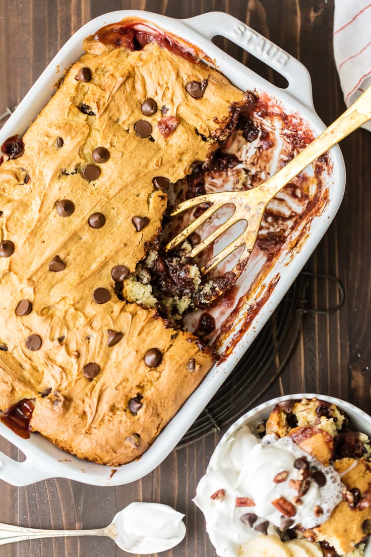 cake in a white baking dish, with a gold spatula