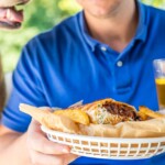 a man holding a basket that has a brisket burrito in it