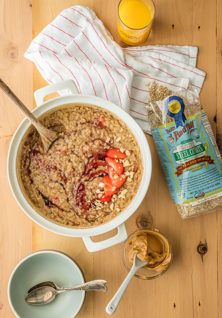 pot of peanut butter and jelly oatmeal on a table with a bag of oats and a dish towel