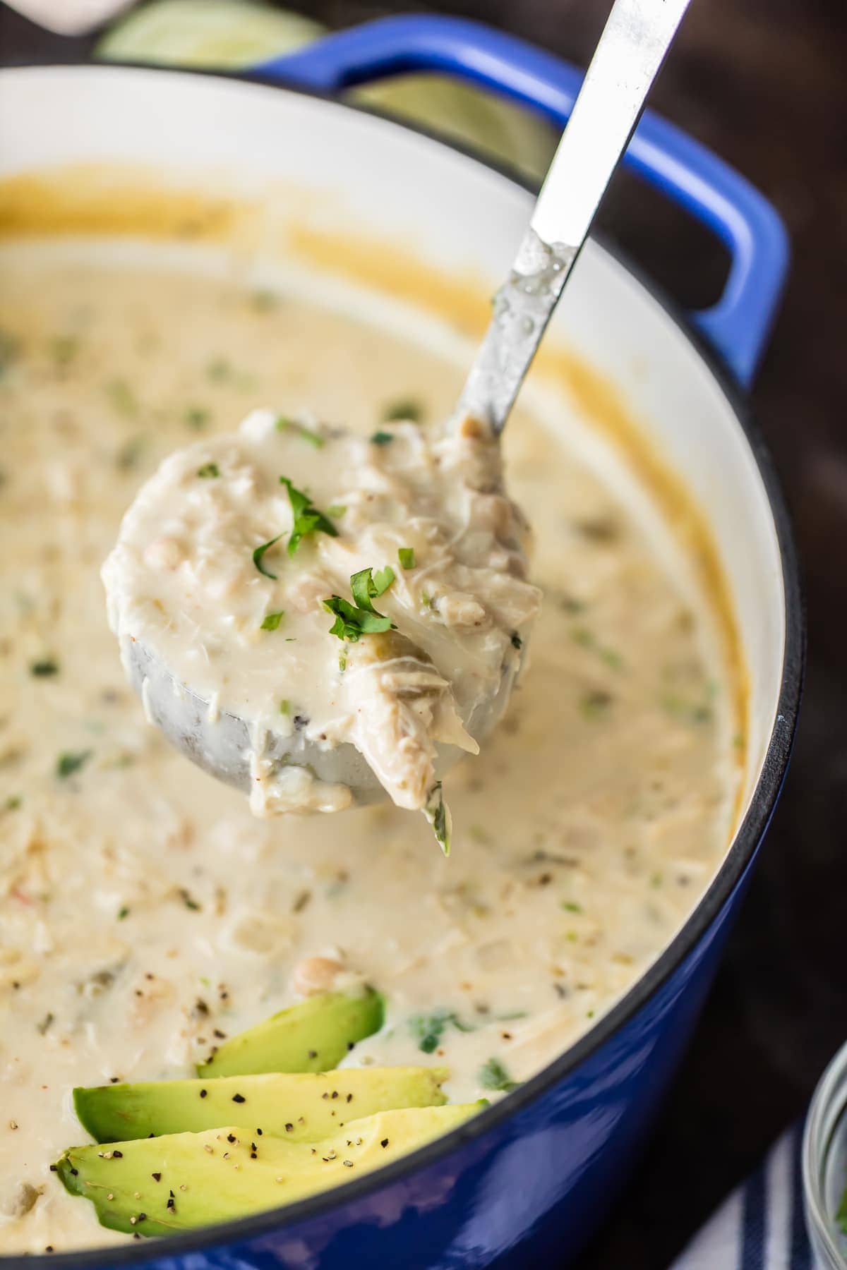close up on a ladle scooping white chicken chili out of a large pot