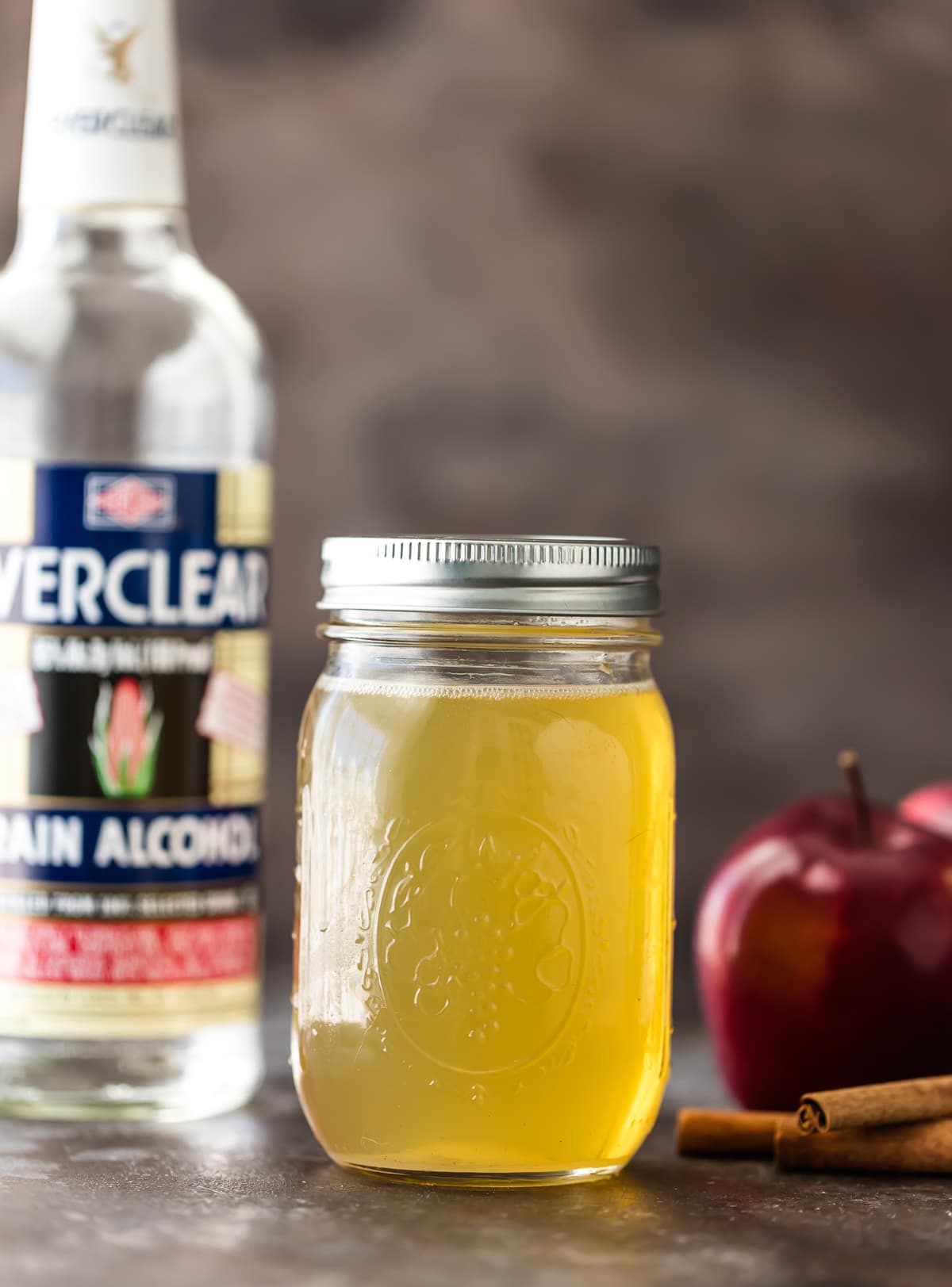 A jar of homemade apple vodka next to a bottle of everclear