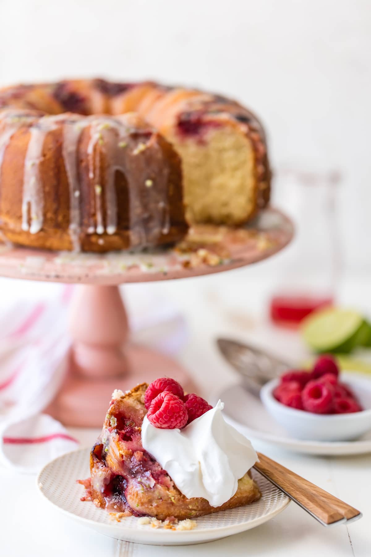 Raspberry cake on a pink cake stand, with a single slice taken out