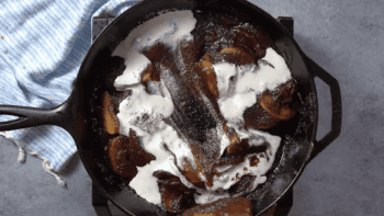 A skillet filled with peaches and cream topped with apple butter.