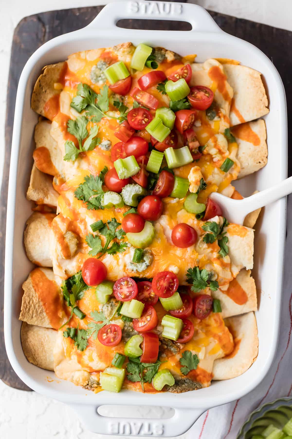 Buffalo Chicken Enchiladas topped with tomatoes, celery, cilantro