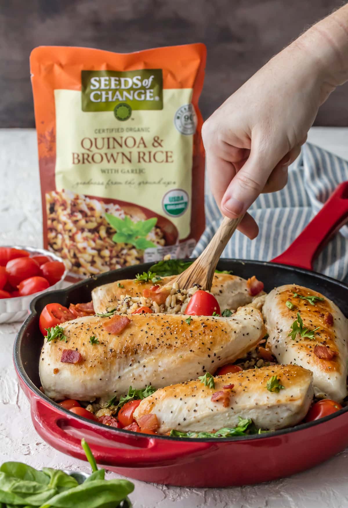 Red skillet filled with chicken and rice, spinach, tomatoes, and bacon