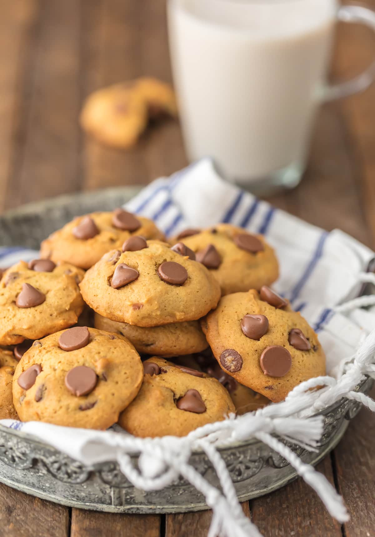 A plate of chocolate chip cookies made with applesauce next to a glass of milk