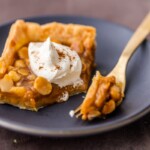 caramel macadamia nut pumpkin pie bar topped with whip cream on blue plate with fork