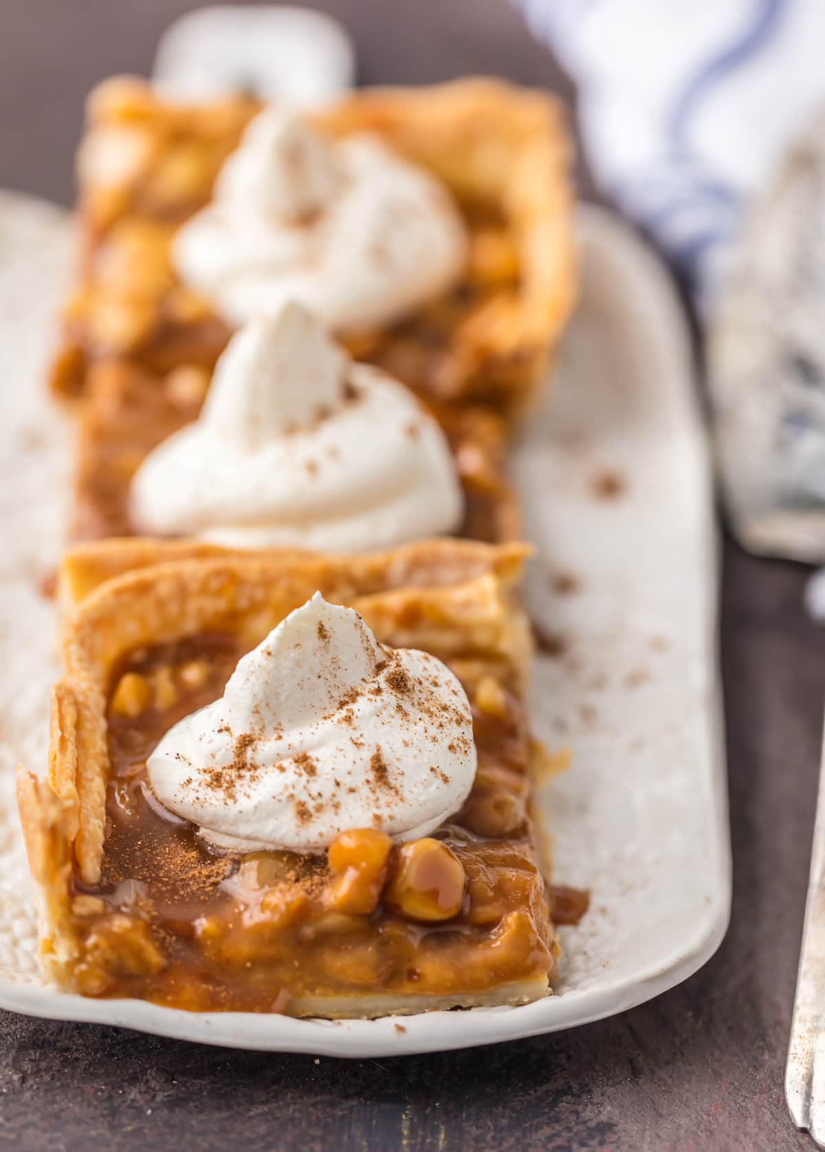 Pumpkin Pie bars lined up on a plate, topped with whipped cream