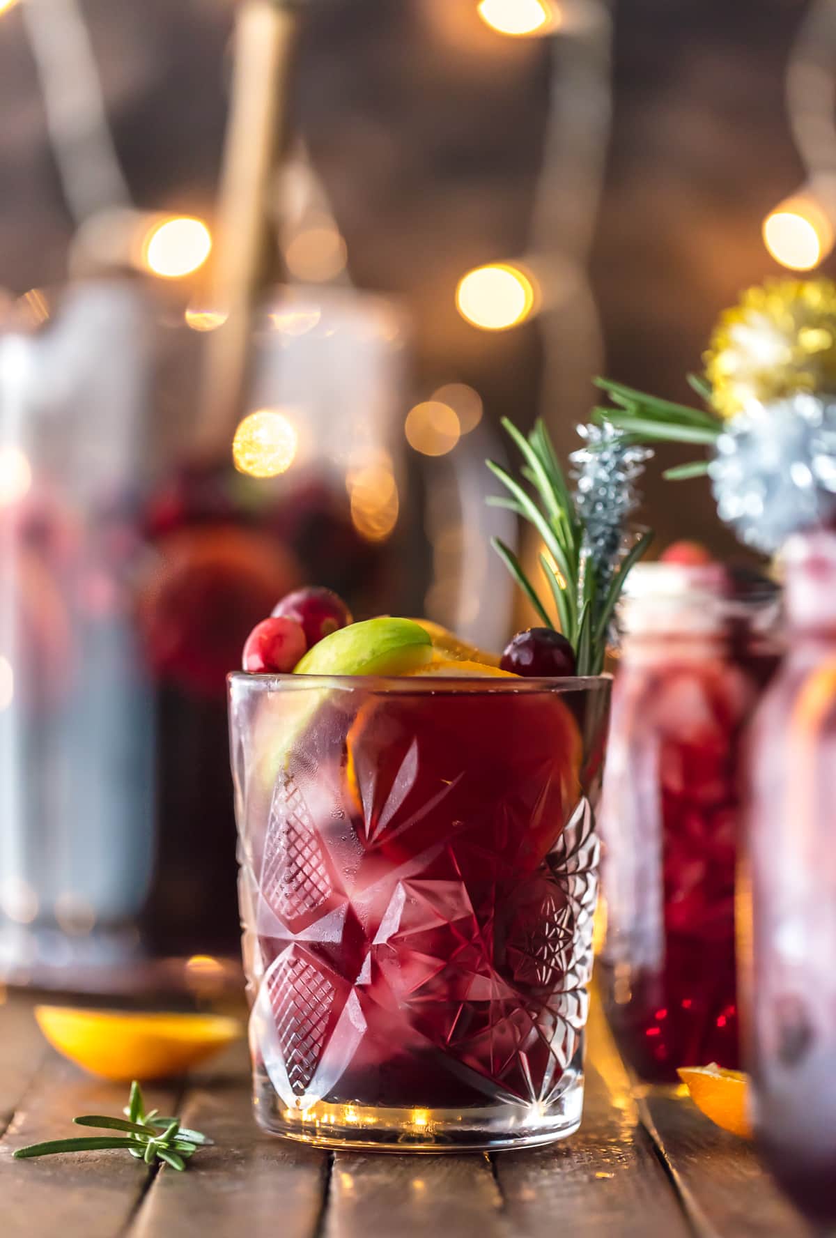 Easy Holiday Sangria recipe in a glass with rosemary and sliced fruit