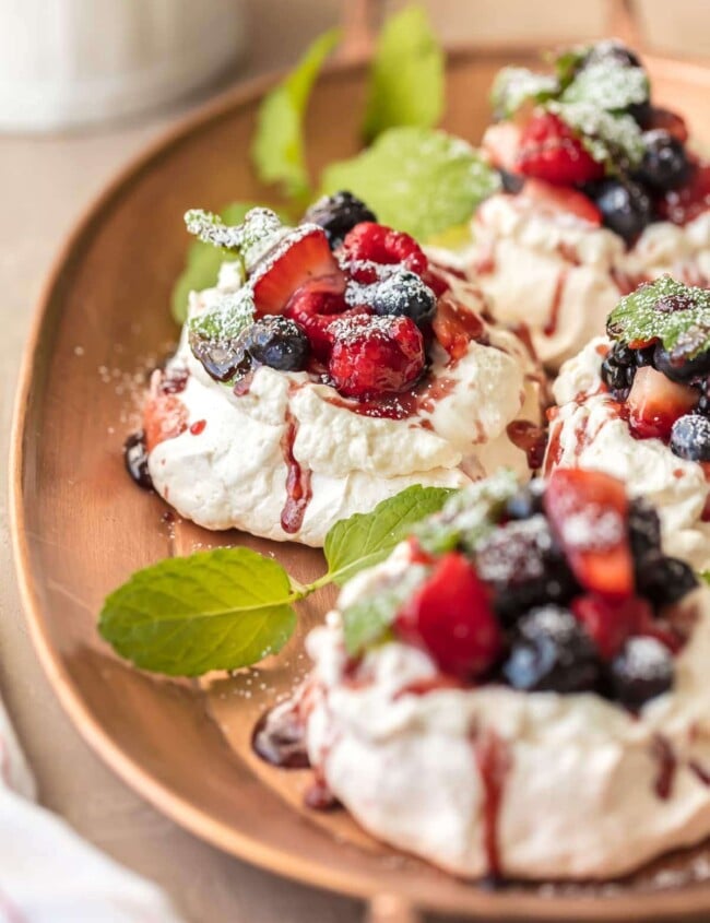 MINI PAVLOVAS topped with fresh fruit, whipped cream, and fruit syrup is the ULTIMATE holiday dessert. This mini pavlova recipe is the perfect dessert for Christmas or any celebration. They're beautiful, delicious, and EASY to make!